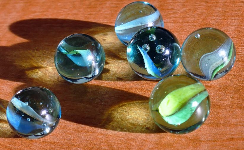 six blue and green marbles on brown surface